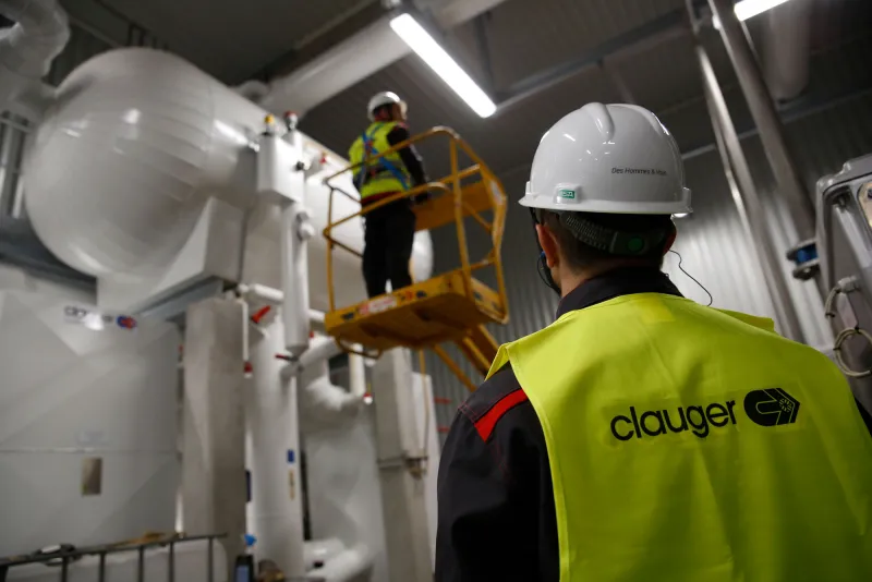 Técnicos de Clauger trabajando junto a tanques de proceso en plataforma elevada.